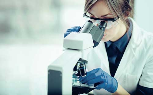 Female scientist looking through microscope.