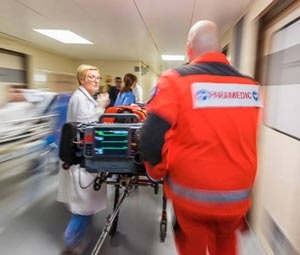 A blurred image of a paramedic rushing a patient down a hospital aisle