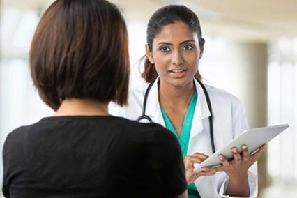 Rear view of patient talking with female doctor with tablet