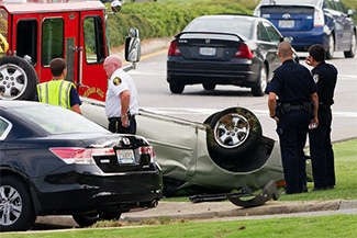 Photo of a car crash scene with police, in which one of the cars is turned upside down