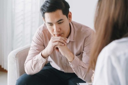 Patient sitting down and listening to a physician in a clinical setting.