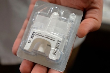 Close-up of hand holding package of naloxone nasal spray.