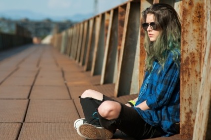 Mujer joven sentada sola al aire libre.