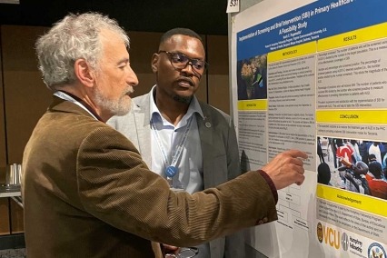 Two men discussing a poster at the 2024 International Forum