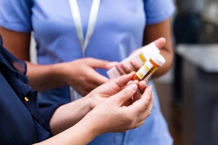 Female pharmacist discusses dosage instructions and drug side effects with a patient.