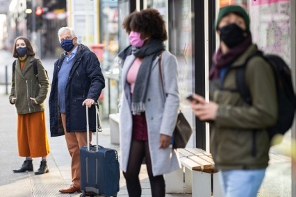Group of people wearing masks, waiting for the bus.