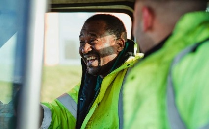 Two road workers sitting in a truck laughing