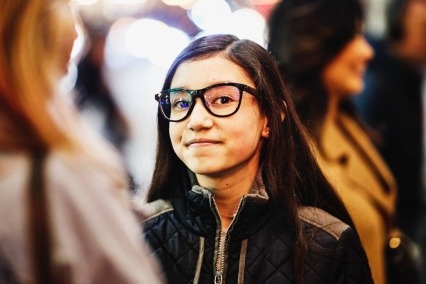 Portrait of a smiling teenage girl outside with friends on a cold evening.