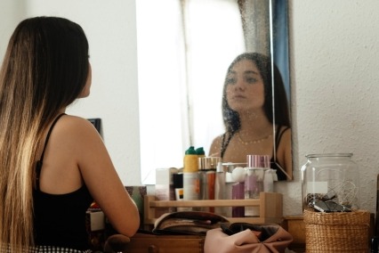 Teenage girl looking at herself in the mirror.