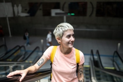 Young woman thoughtfully looking around while moving up on an escalator in a subway station