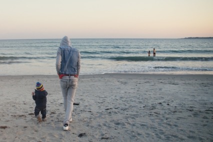 Rearview of a father and toddler taking a sunset walk at the seaside.