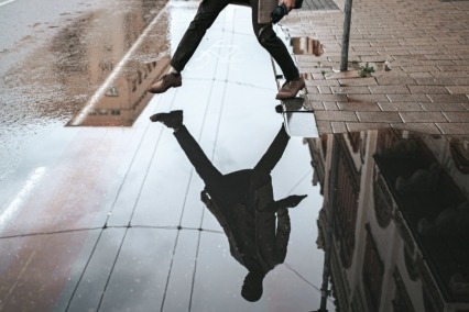 Reflection of man jumping over a puddle