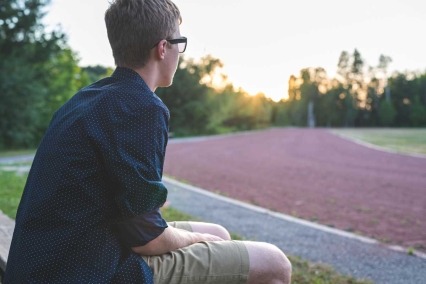 Male teenager sitting on a bench.