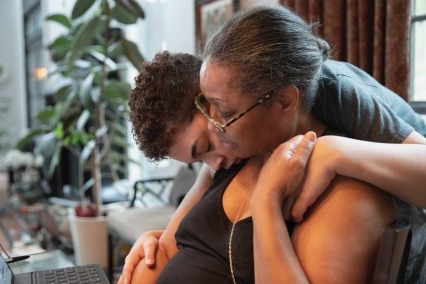 Teen son hugging mother.