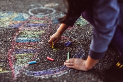 Little girl chalk drawing on asphalt