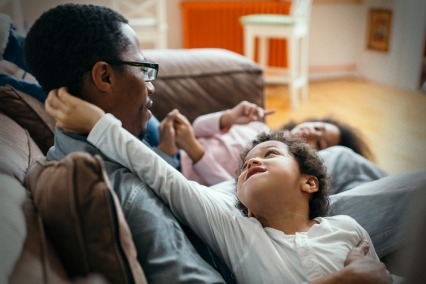 Father sitting on couch with two young children.