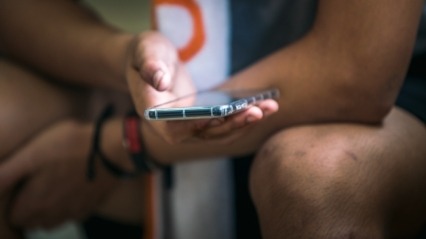 Close up of hand holding smartphone that is lit up. 