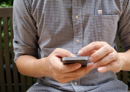 A closeup photo of a man holding a cell phone.