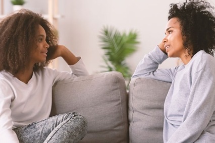 Two women sitting on a couch talking
