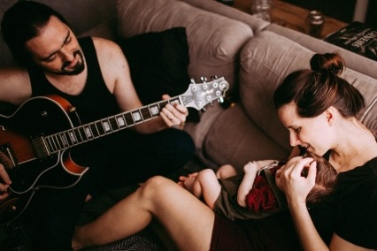 Young family playing music together on couch.