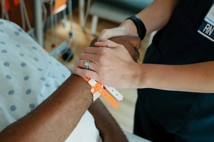 A nurse holding a patient's hand