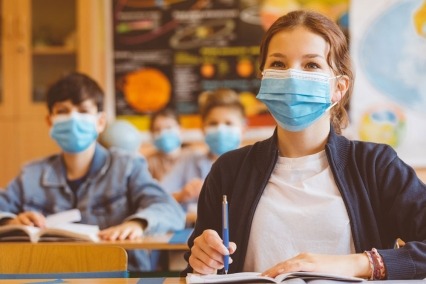 Teenage girl wearing an M95 mask and sitting at the school desk