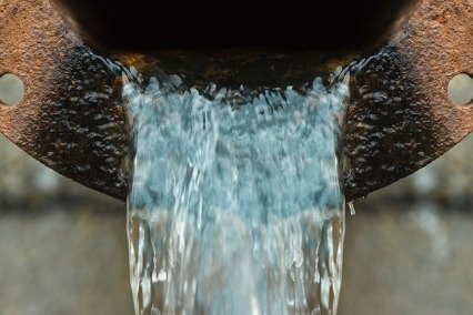Close up of sewer drain with water pouring out