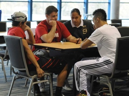 Four male youth sitting together planning event at table