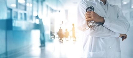 a doctor holding a stethoscope standing in a hospital hallway