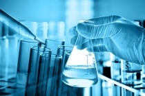 Flask in scientist hand with dropping liquid to test tube