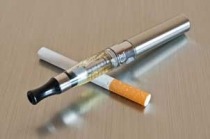 E-cigarette device laying across a cigarette