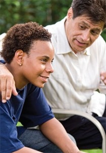 Teenage son listening to father’s advice sitting outside