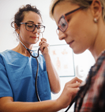 Physician holds stethoscope and listens to patient's heartbeat