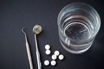 Dental tools, white pills, glass of water