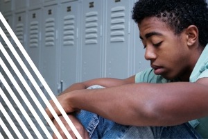 Teen sitting on floor against lockers