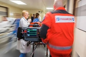 Patient being wheeled down hallway with doctor and paramedic
