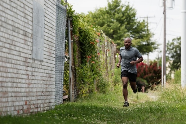 Man running in grass in an urban setting