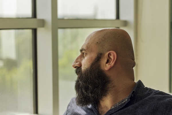 A bearded man looking out a window