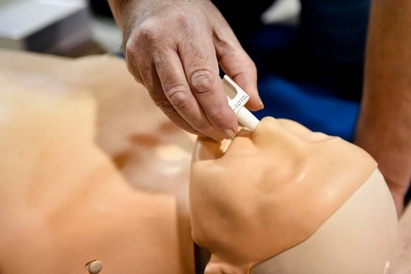 Close-up of an overdose rescue demonstration with naloxone and a mannequin.