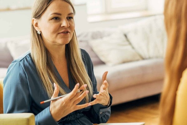 Two women in armchairs are sitting and talking.