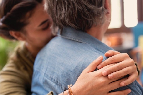 Close-up of adult couple sharing a supportive hug.