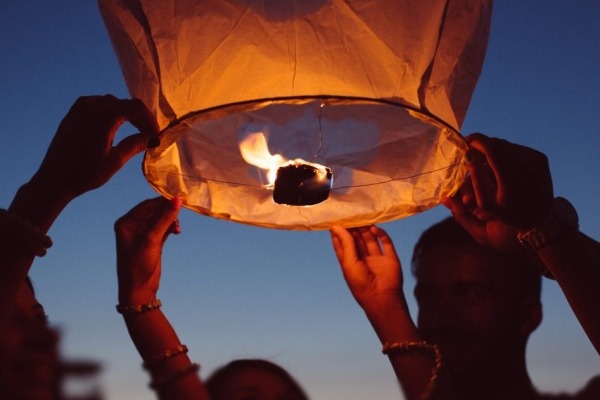 Group of people releasing a paper lantern into the sky at night.
