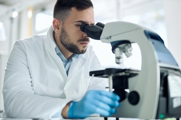Young male scientist working on a microscope in laboratory.