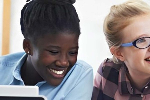 Two teenage girls looking at something and smiling.
