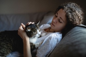 A young girl laying on a couch holding a cat.