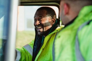 Two road workers sitting in a truck laughing