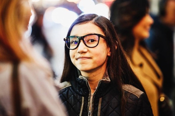 Retrato de una adolescente sonriente afuera con amigos en una noche fría.