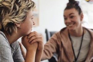 Side view of female health professional talking with a teenager.