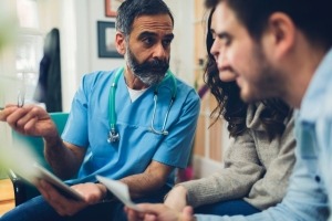 Male nurse consulting a man and a woman in medical setting. 