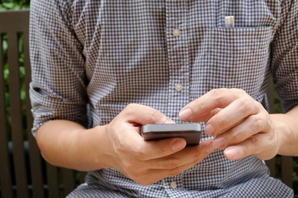 A closeup photo of a man holding a cell phone.